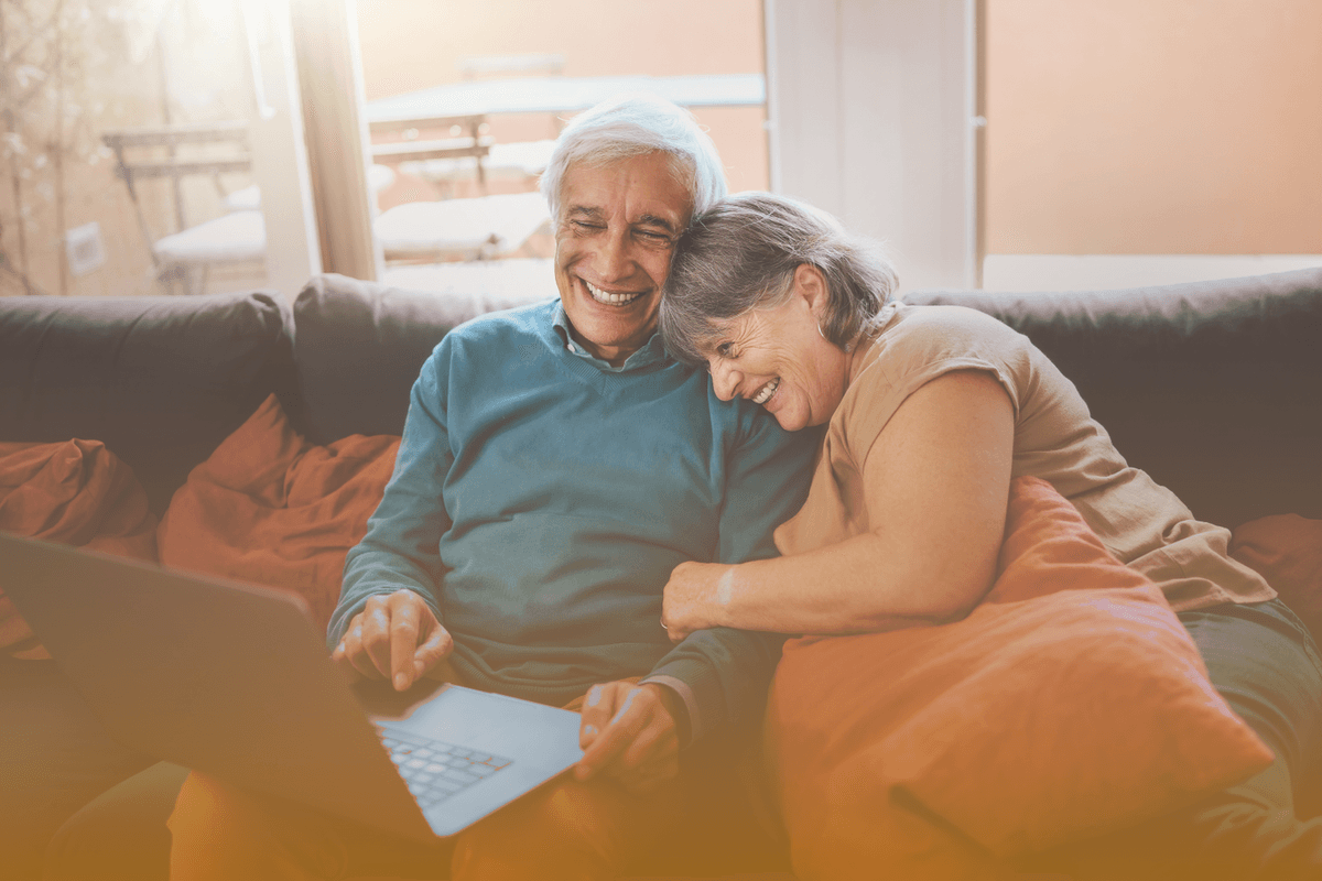 retired couple laughing and surfing the web on couch