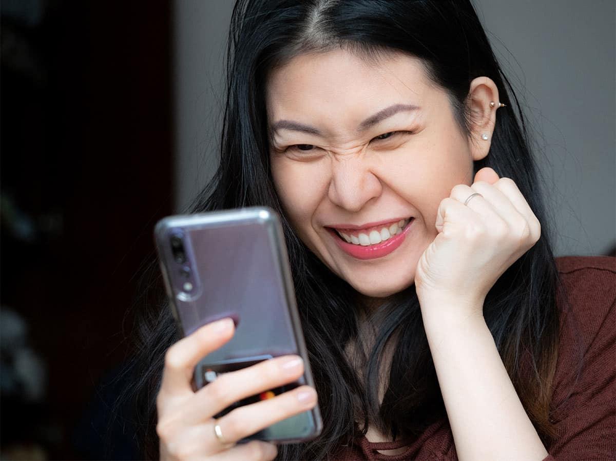 women smiling while looking at phone